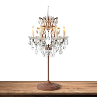 Warmly lit Moorizon Rustline crystal table lamp with candle-style bulbs, curved metal arms, and hanging crystal drops on a white background