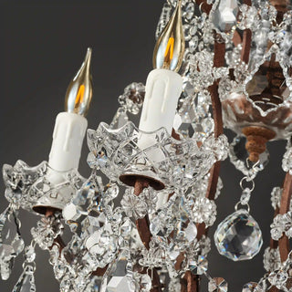 Warmly lit Moorizon Rustline crystal table lamp detail with candle-style light, hanging crystal drops, and ornate metal arms on a dark background