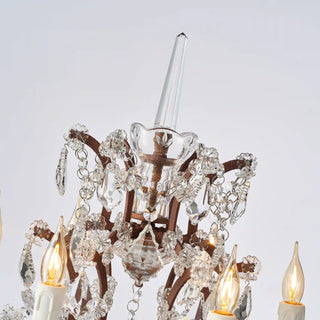 Warmly lit Moorizon Rustline crystal table lamp detail with candle-style bulbs, layered crystal accents, and ornate metal frame details on a white background