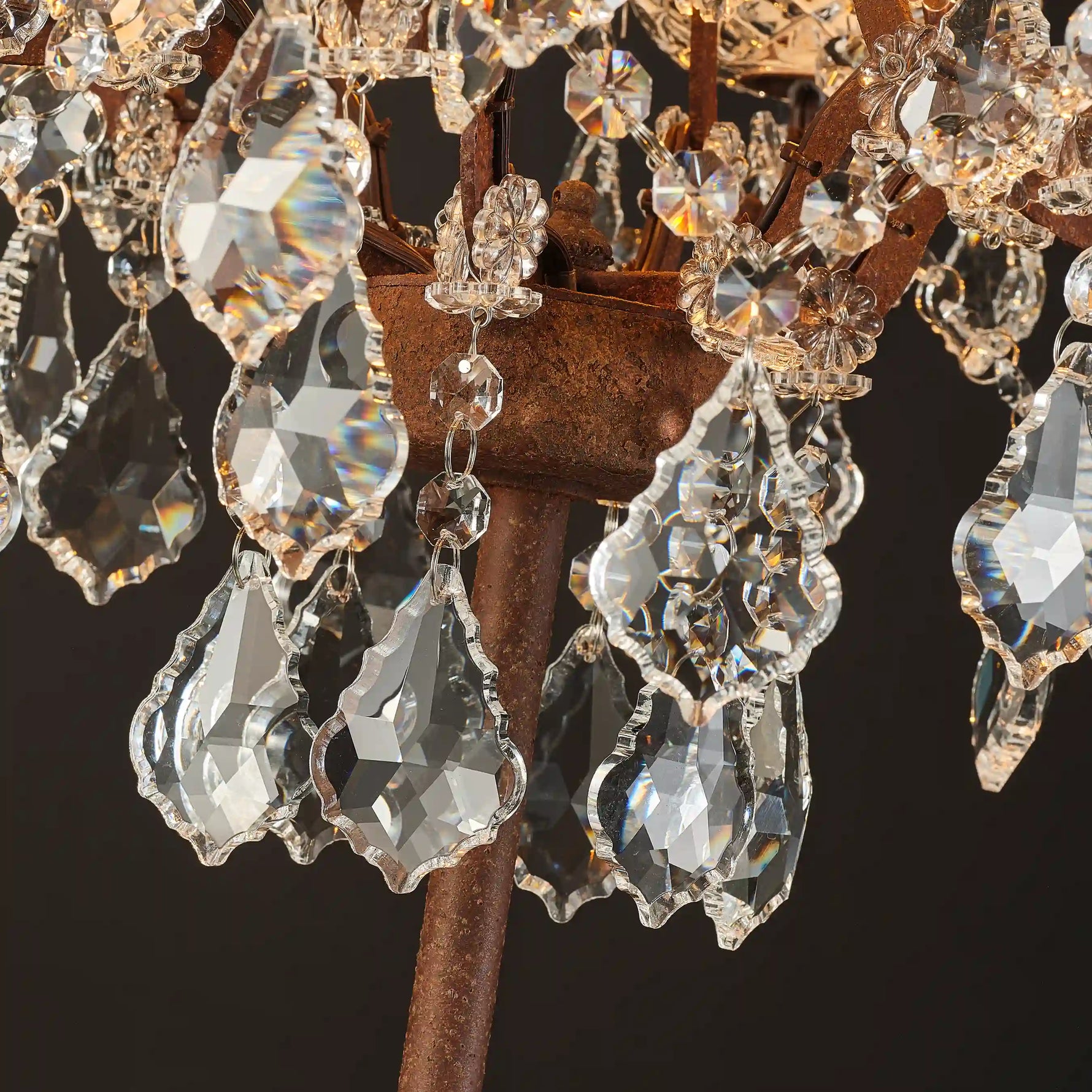 Warmly lit Moorizon Rustline crystal table lamp detail showing faceted crystal drops, metal frame accents, and candle-style light on a dark background