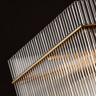 Lit side detail of the Timelore Rectangular Chandelier with individually suspended clear glass rods and warm brass accents in a black background. 
