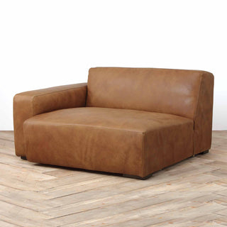 angle view of Rustic Haven right arm sectional sofa piece in cognac brown leather, wood floor background