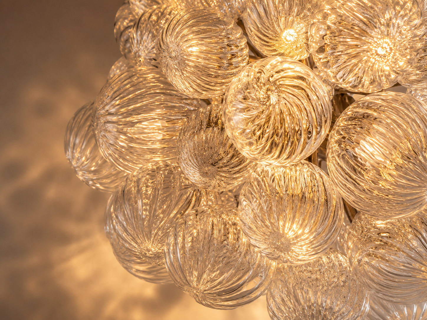 Illuminated spiral bubble glass elements refracting warm light through layered sculptural textures.