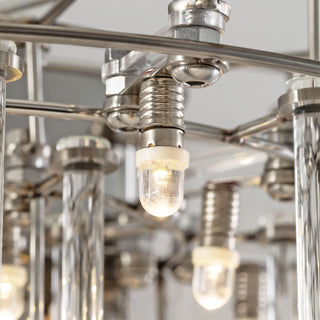 Close-up of small Stardust Sconce Lamp capturing intricate details of the metal frame and clear glass tubes in a showroom setting
