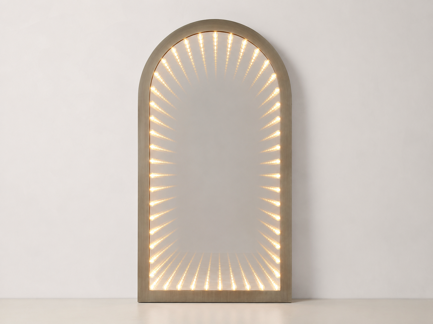 Full view of the Timeless Gate arched wall mirror illuminated against a neutral wall