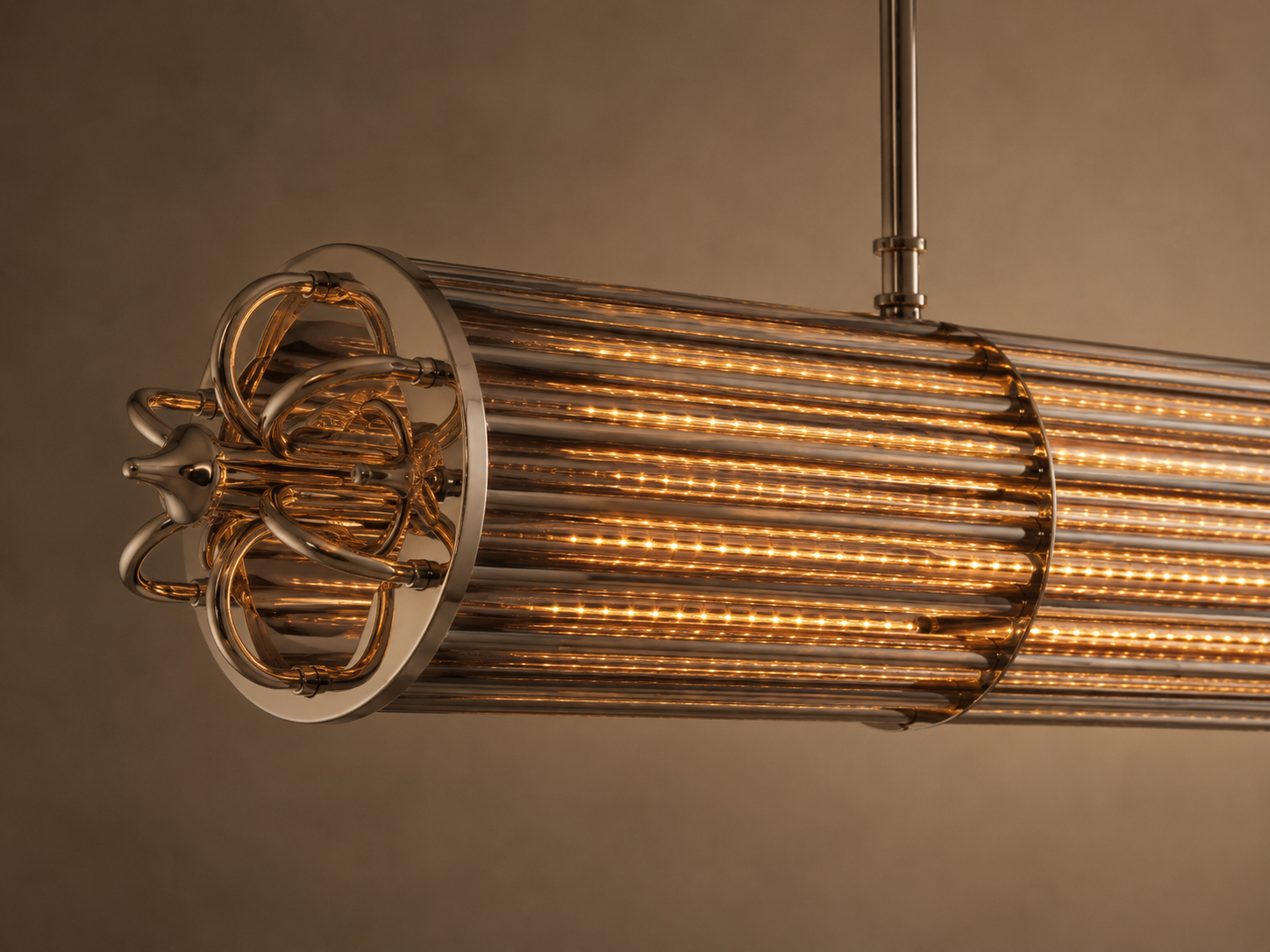 Close-up of the illuminated Urban Glow chandelier with warm amber ribbed glass rods and polished metal detailing.