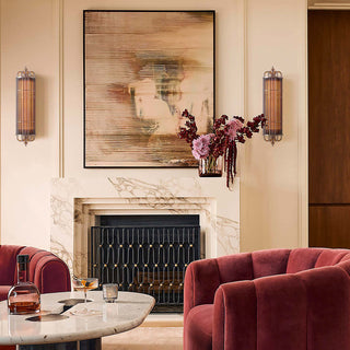 Urban Glow sconce elegantly mounted in a luxury dining room with velvet chairs, floral arrangement, and layered wall art, casting a warm decorative glow