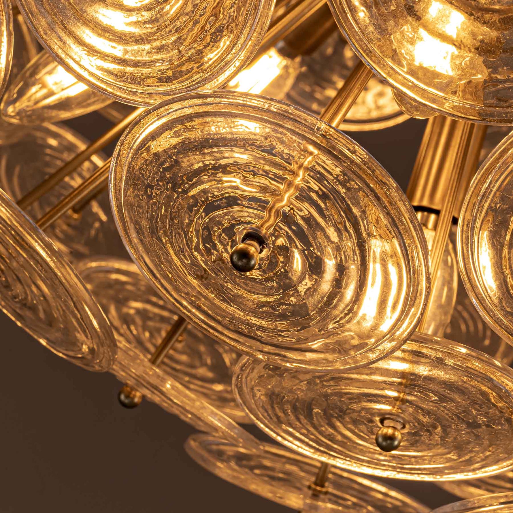 Warm detail view of Wavora Demi chandelier with rippled glass discs